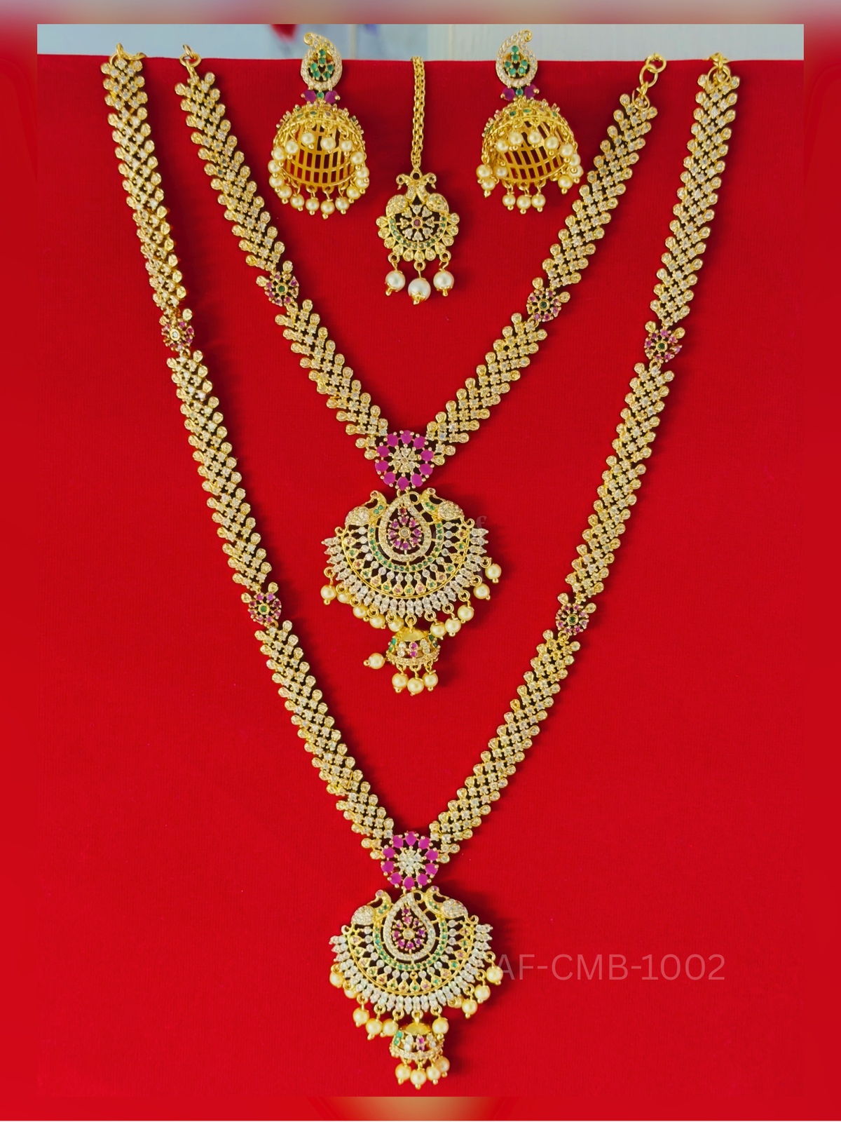 A dazzling two-layer set of sparkling white-stone chains with peacock chandbali pendants and pearl-fringed jhumka drops, completed with jhumka earrings and maang tikka.