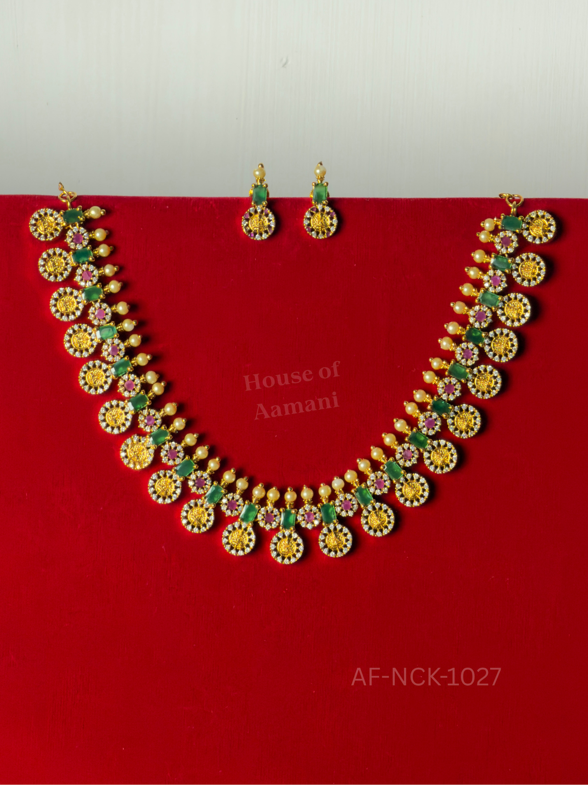 A traditional-style necklace of gold coin medallions ringed in crystals, set with emerald stones and pearl drops, with matching earrings.