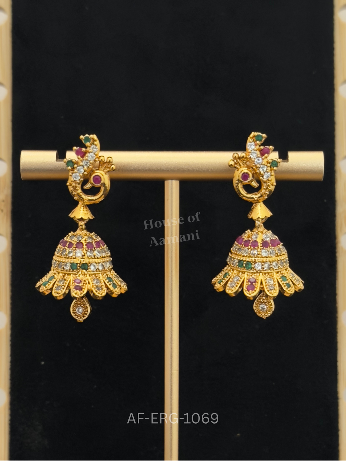 Peacock tops lead to petal-edged bell jhumkas set with ruby, emerald, and crystal stones, finished with a delicate teardrop.