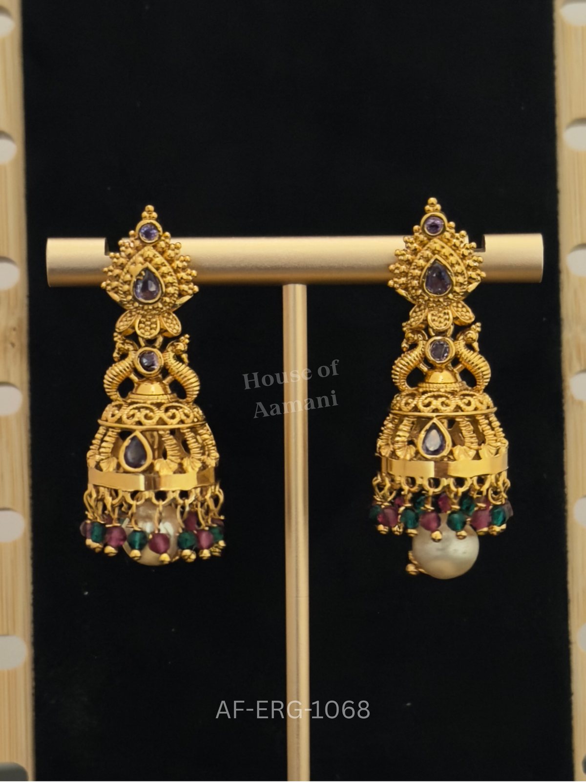 Antique gold jhumkas with soft lavender stones, ruby-green bead drops, and a cream pearl for a distinctive look.