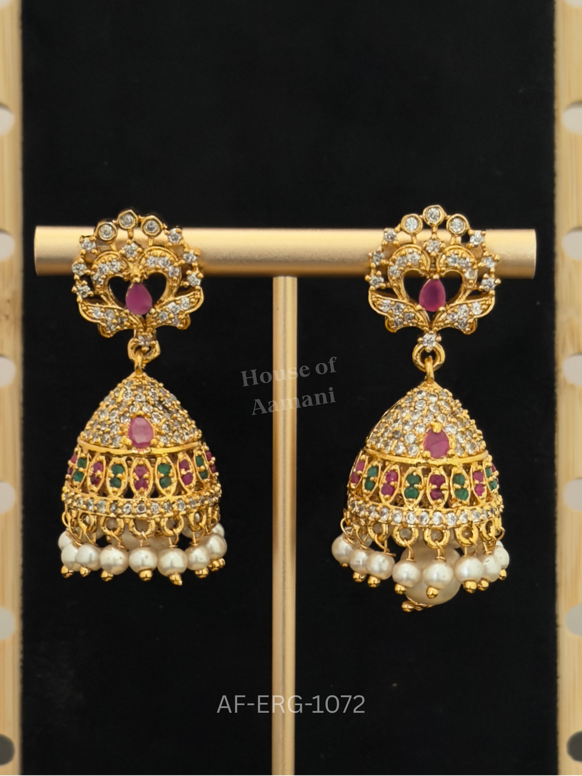 Crystal scroll tops with a ruby drop lead to a cone-shaped dome with jewelled bands and a cascade of white pearls.