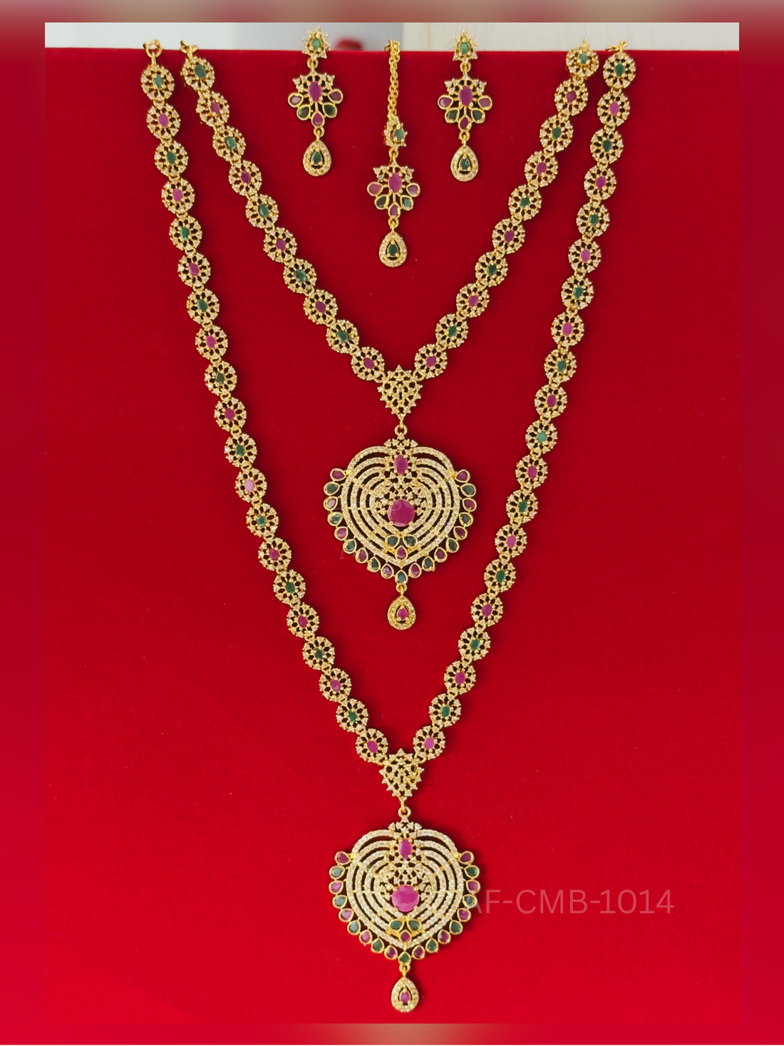 Circular ruby and emerald links flow into a striking heart-shaped pendant of concentric crystal rings, with a coordinating short necklace, earrings, and maang tikka.