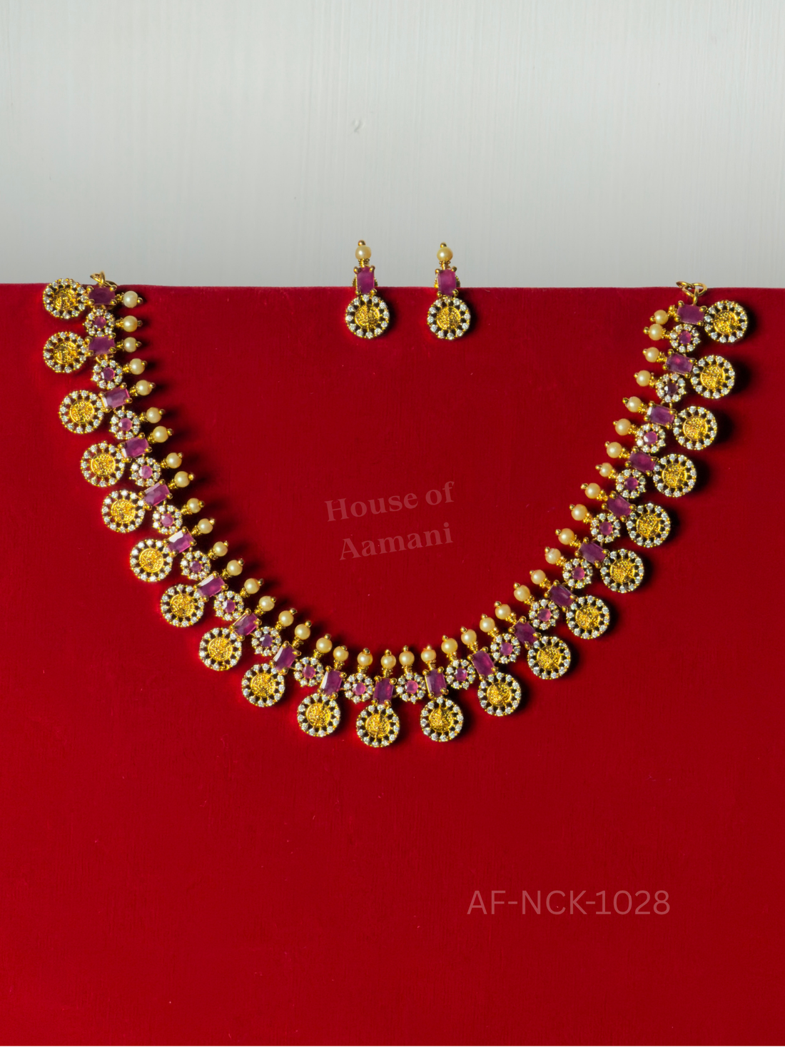 Gold coin medallions framed in sparkling crystals and alternating with ruby-pink stones and pearl drops, paired with matching earrings.