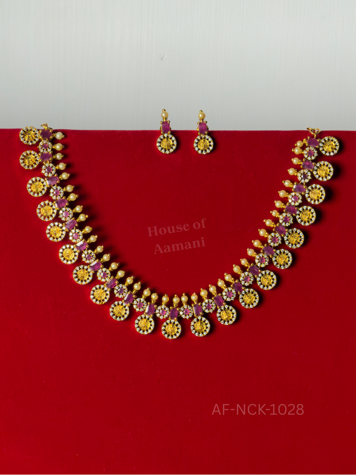 Gold coin medallions framed in sparkling crystals and alternating with ruby-pink stones and pearl drops, paired with matching earrings.