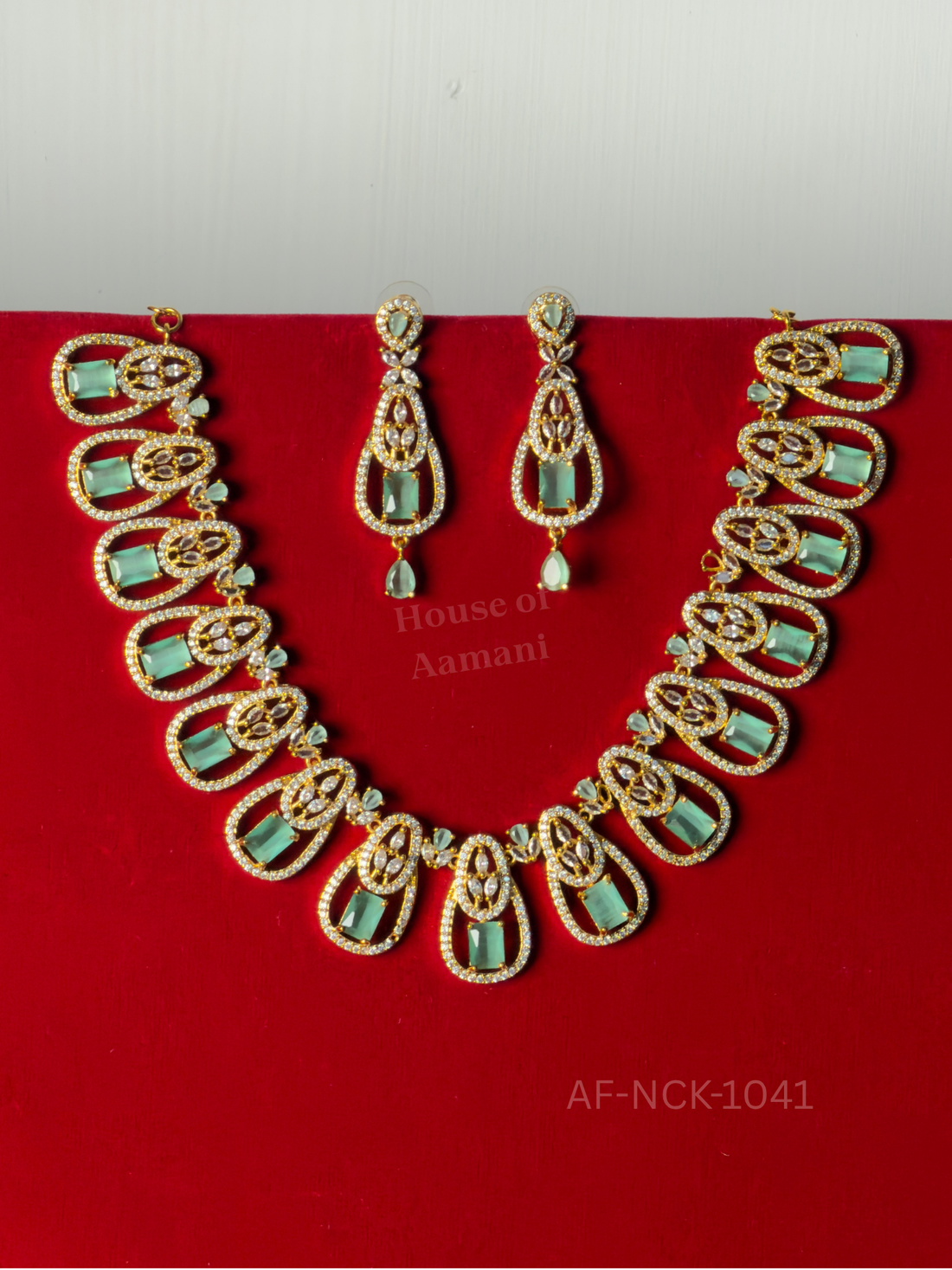 Sparkling teardrop frames holding mint-green rectangular stones, paired with matching drop earrings.