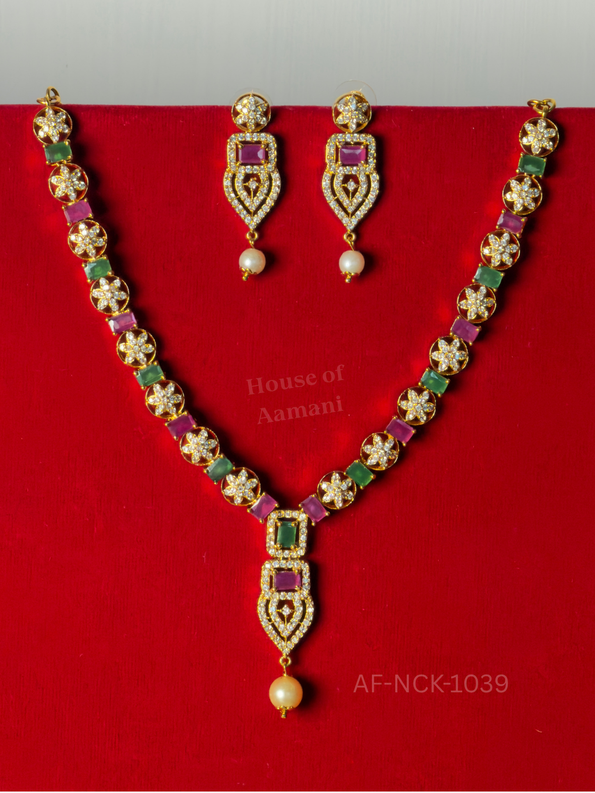 Crystal flower discs alternating with ruby and mint-green stones, ending in a pearl-drop pendant with matching earrings.