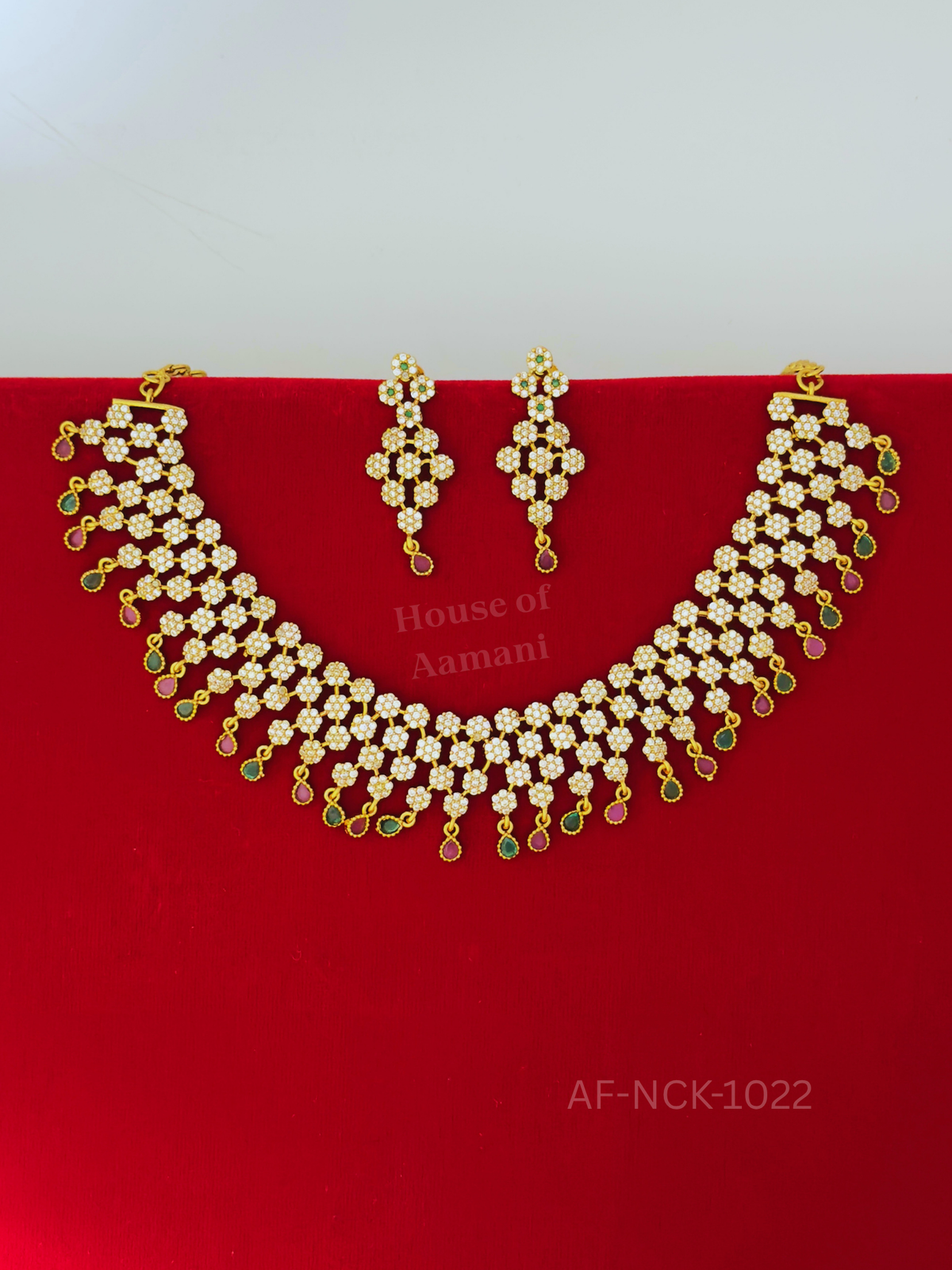 A dazzling choker of clustered white-stone blossoms, edged with delicate ruby and emerald teardrop danglers and completed by matching earrings.