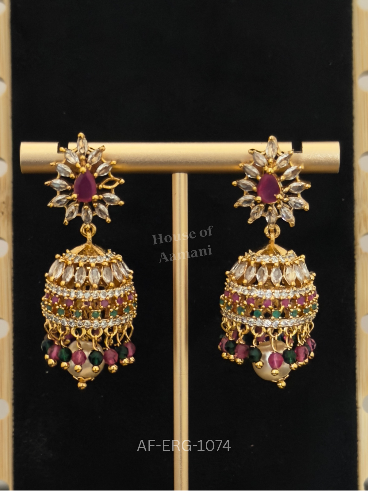A marquise crystal sunburst top leads to a jewelled dome with ruby, emerald, and white bands and a fringe of beads and a pearl.