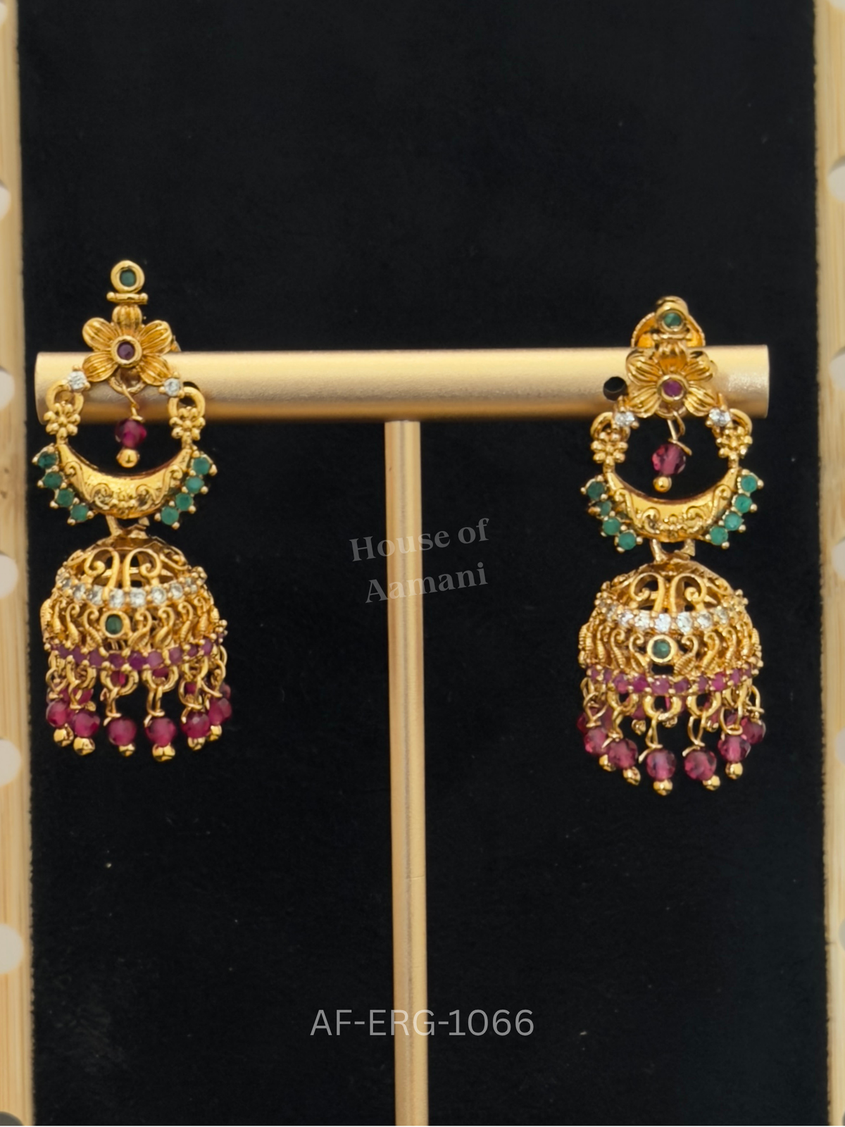 Floral chandbali tops with emerald accents lead to a filigree dome edged with ruby stones and ruby bead drops.