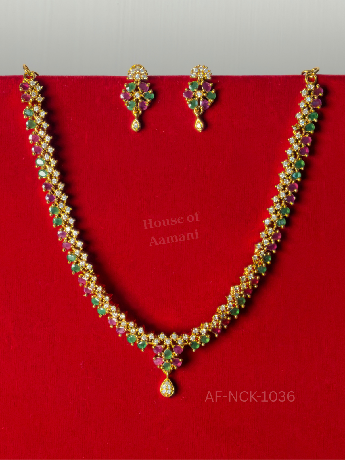 A lightweight zigzag necklace of tiny ruby, emerald and white stones with a small teardrop pendant and matching earrings.