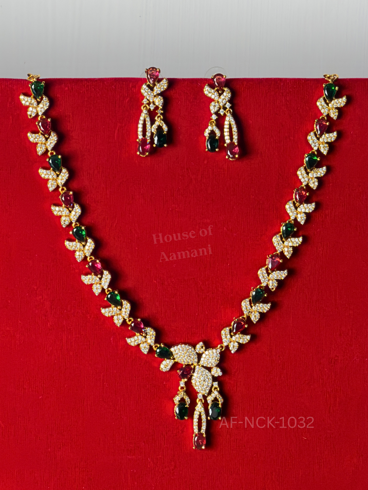 Crystal leaf links alternating with ruby and emerald teardrop stones, ending in a tassel-style pendant with matching earrings.