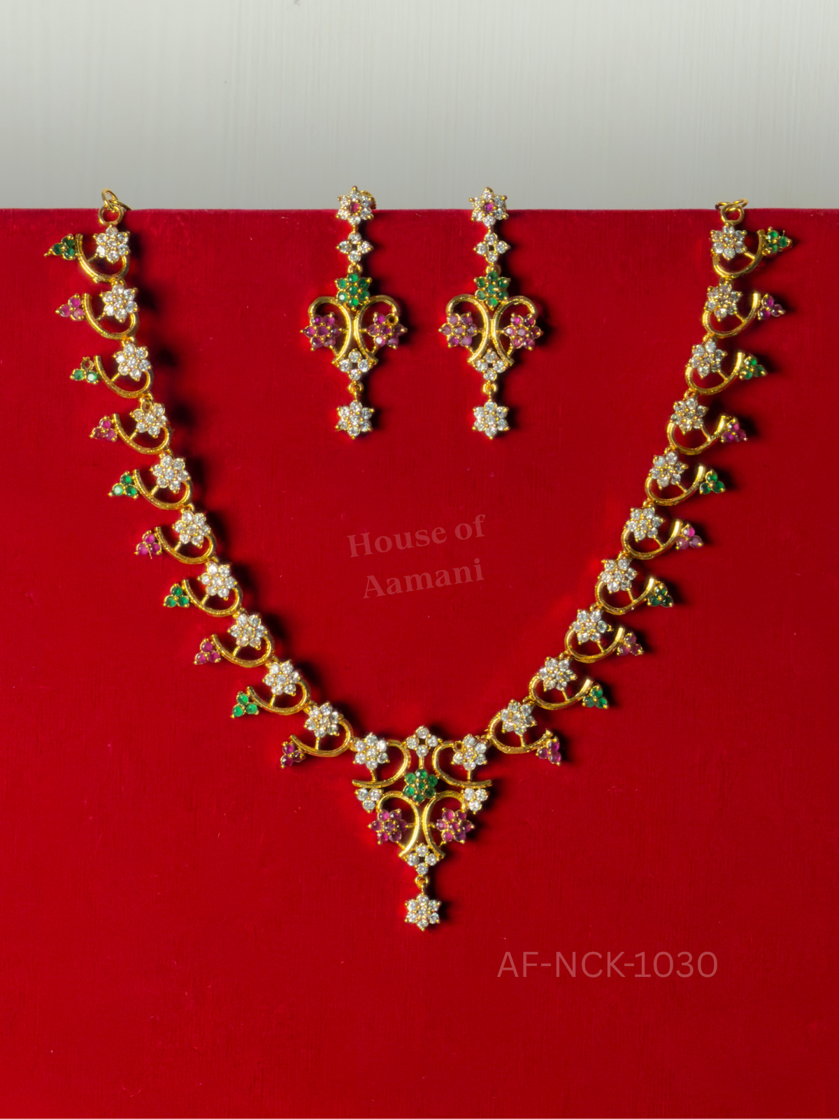 Curling gold vines set with white crystal flowers and clusters of ruby and emerald stones, with matching drop earrings.