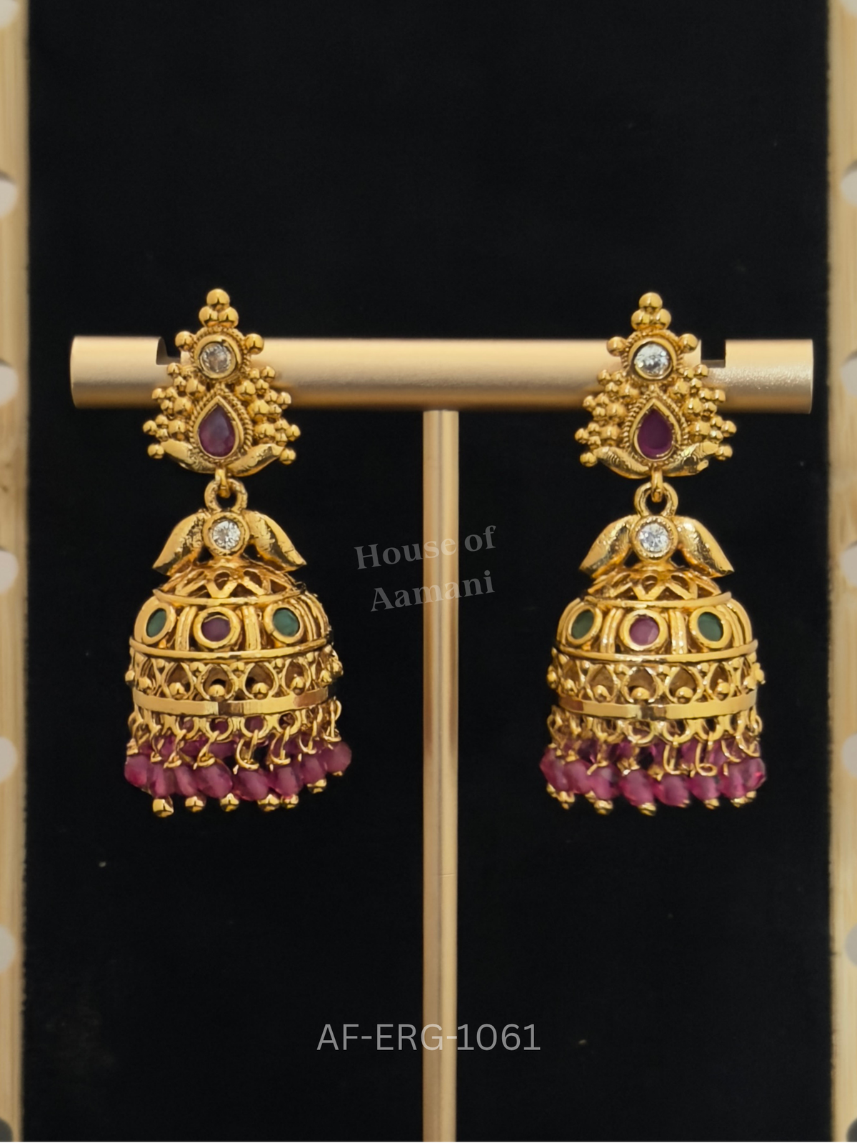Textured gold jhumkas with twin bird motifs, ruby and emerald stones, and a fringe of ruby-pink beads.