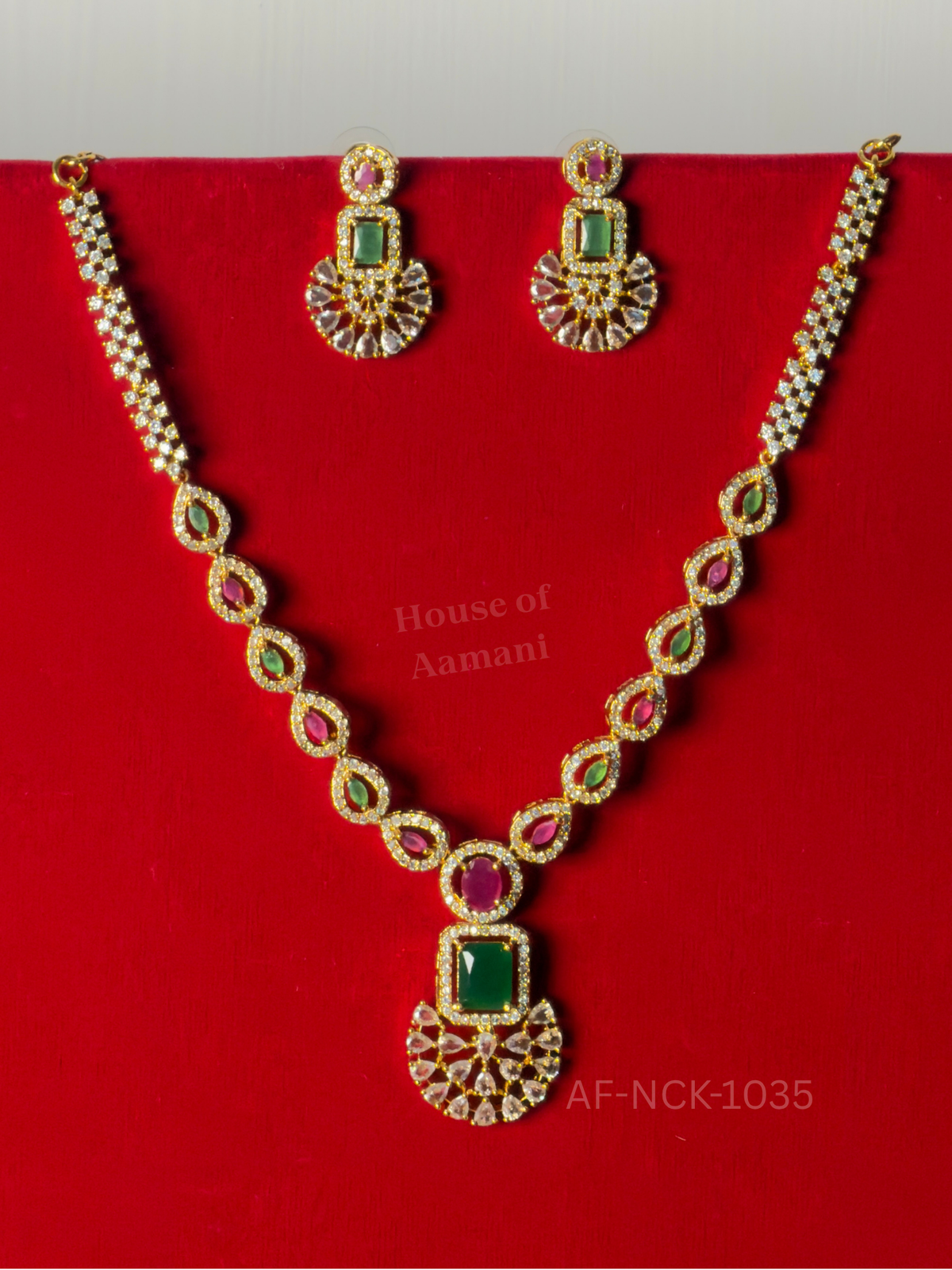 Teardrop links of ruby and emerald lead to a crystal fan-shaped pendant, paired with matching drop earrings.