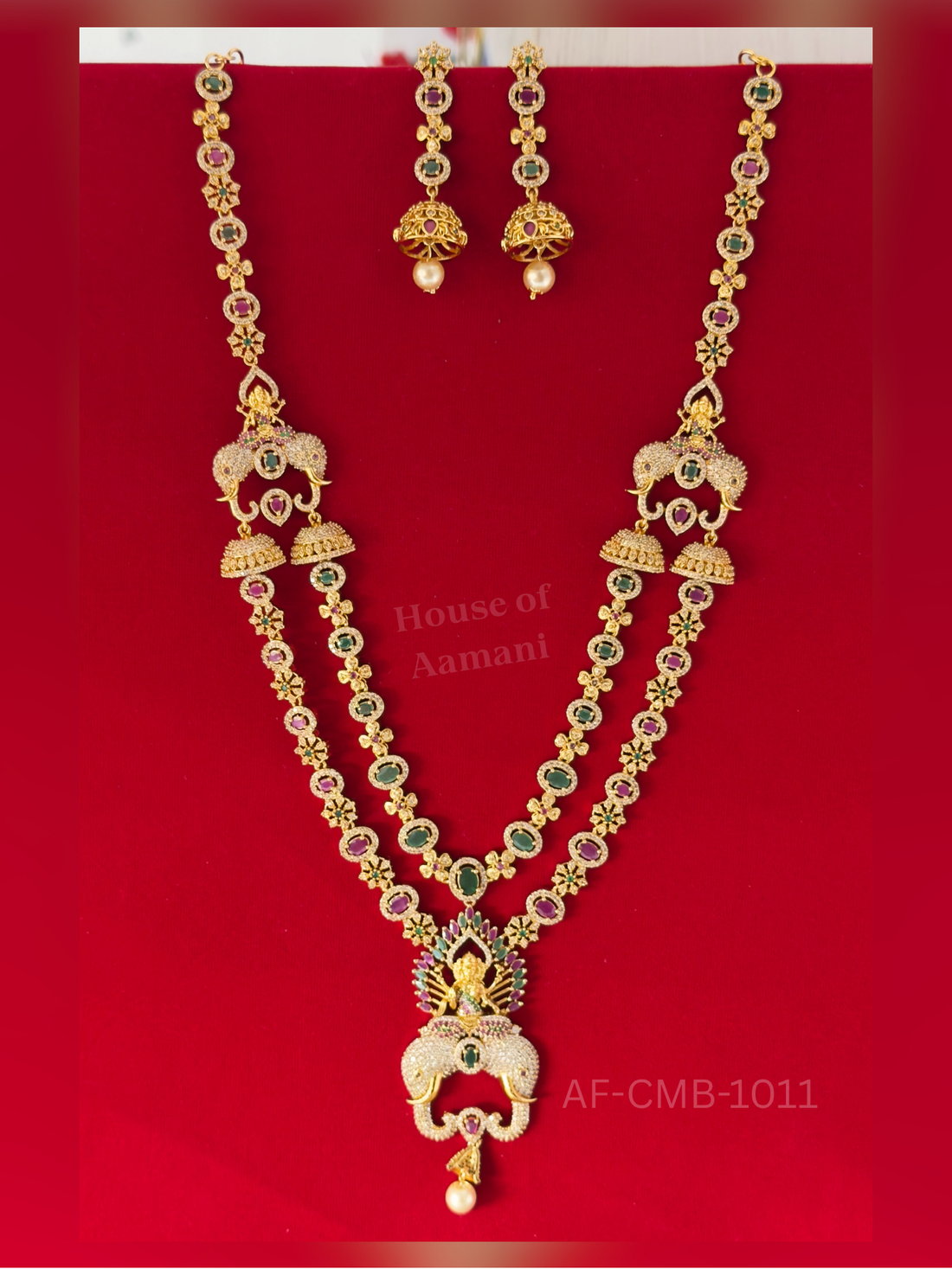 A two-strand set of ruby and emerald ovals with twin elephant motifs and a seated Lakshmi pendant, completed with jhumka earrings.