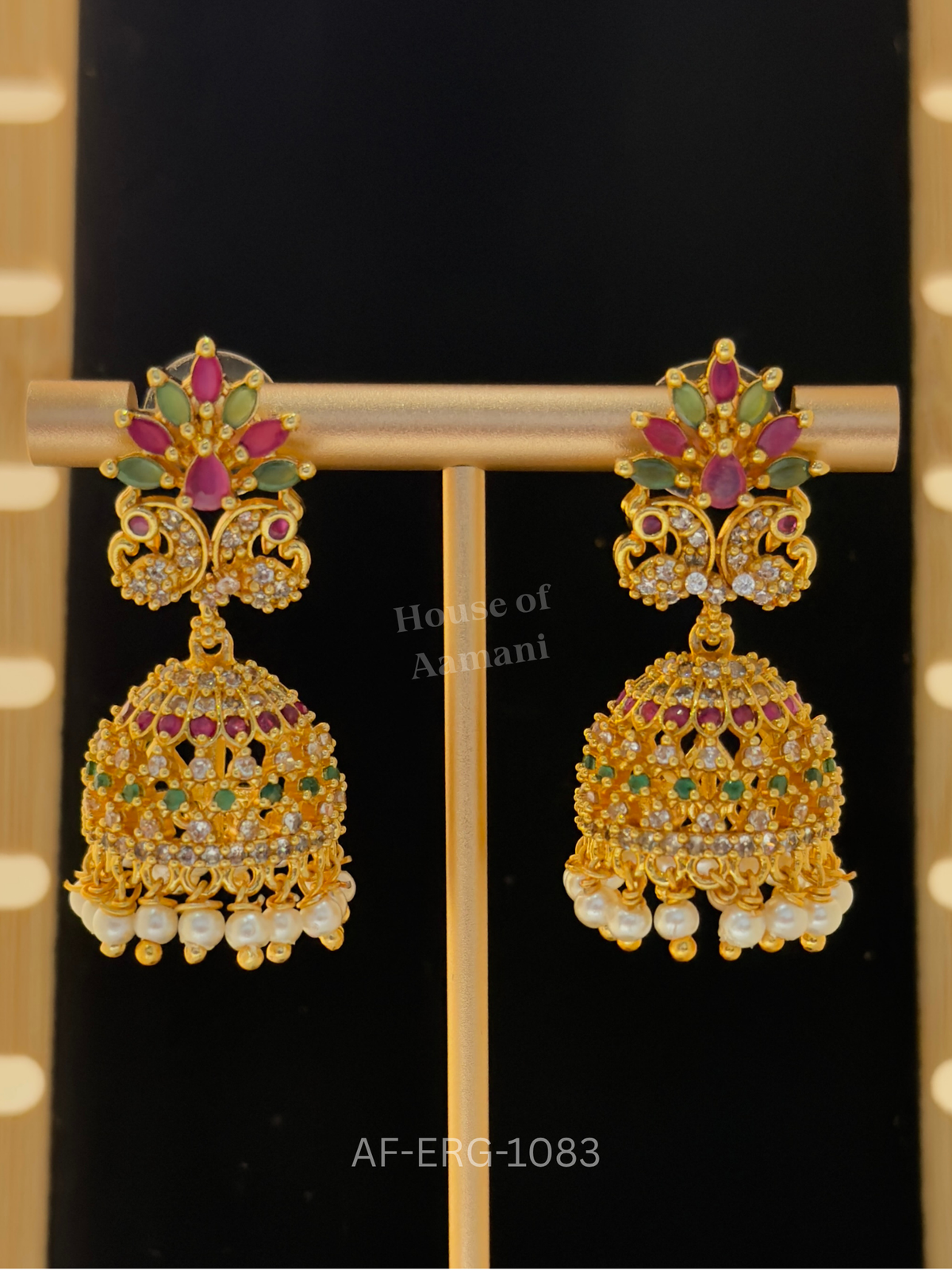 A ruby and emerald lotus crown over twin peacocks leads to a crystal cage dome bordered with delicate pearls.