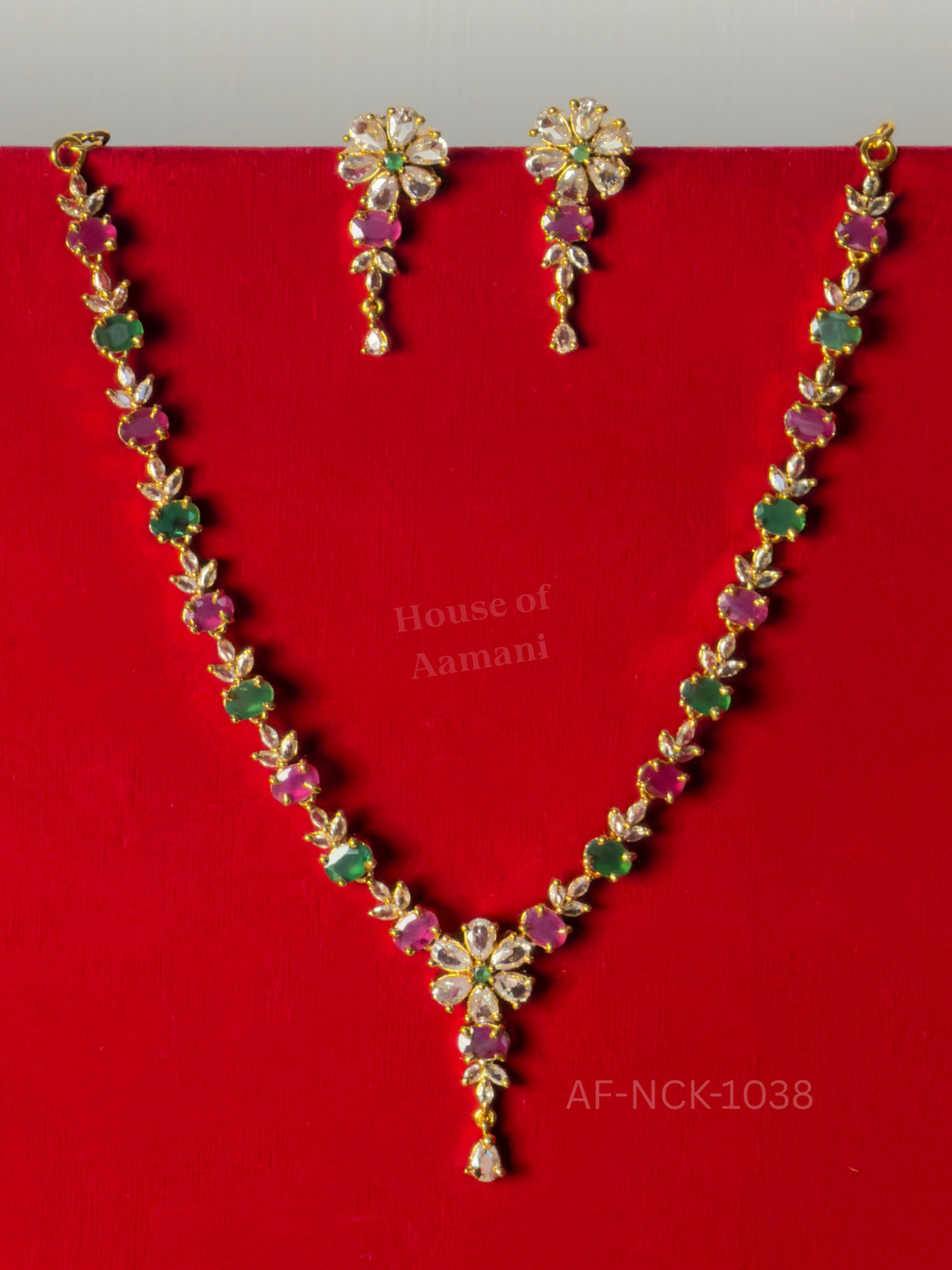 Oval rubies and emeralds separated by crystal leaf sprigs, with a floral centre drop and matching flower earrings.