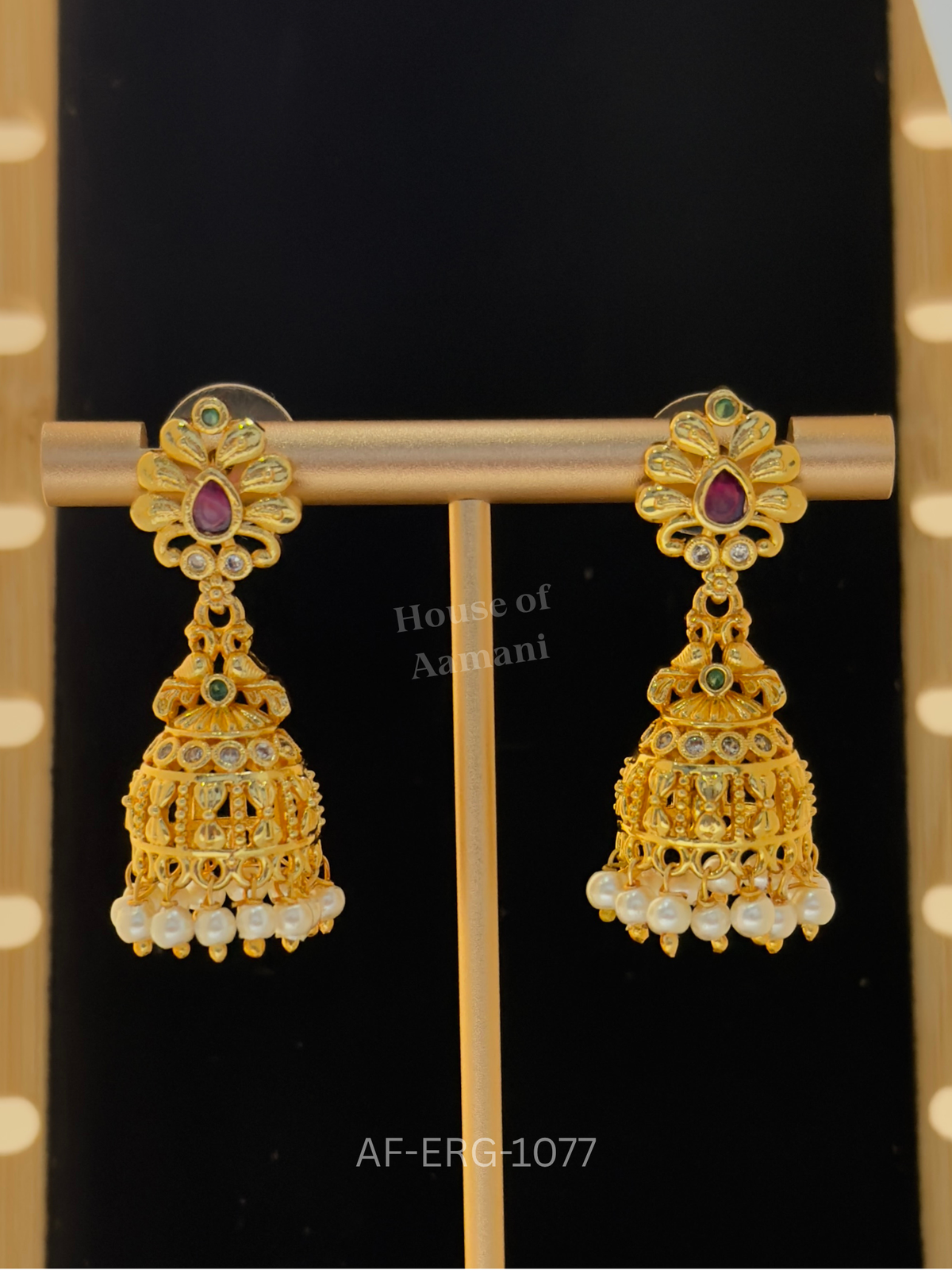 Petal-shaped tops with a ruby teardrop lead to intricate golden cage domes with stone accents and pearl drops.