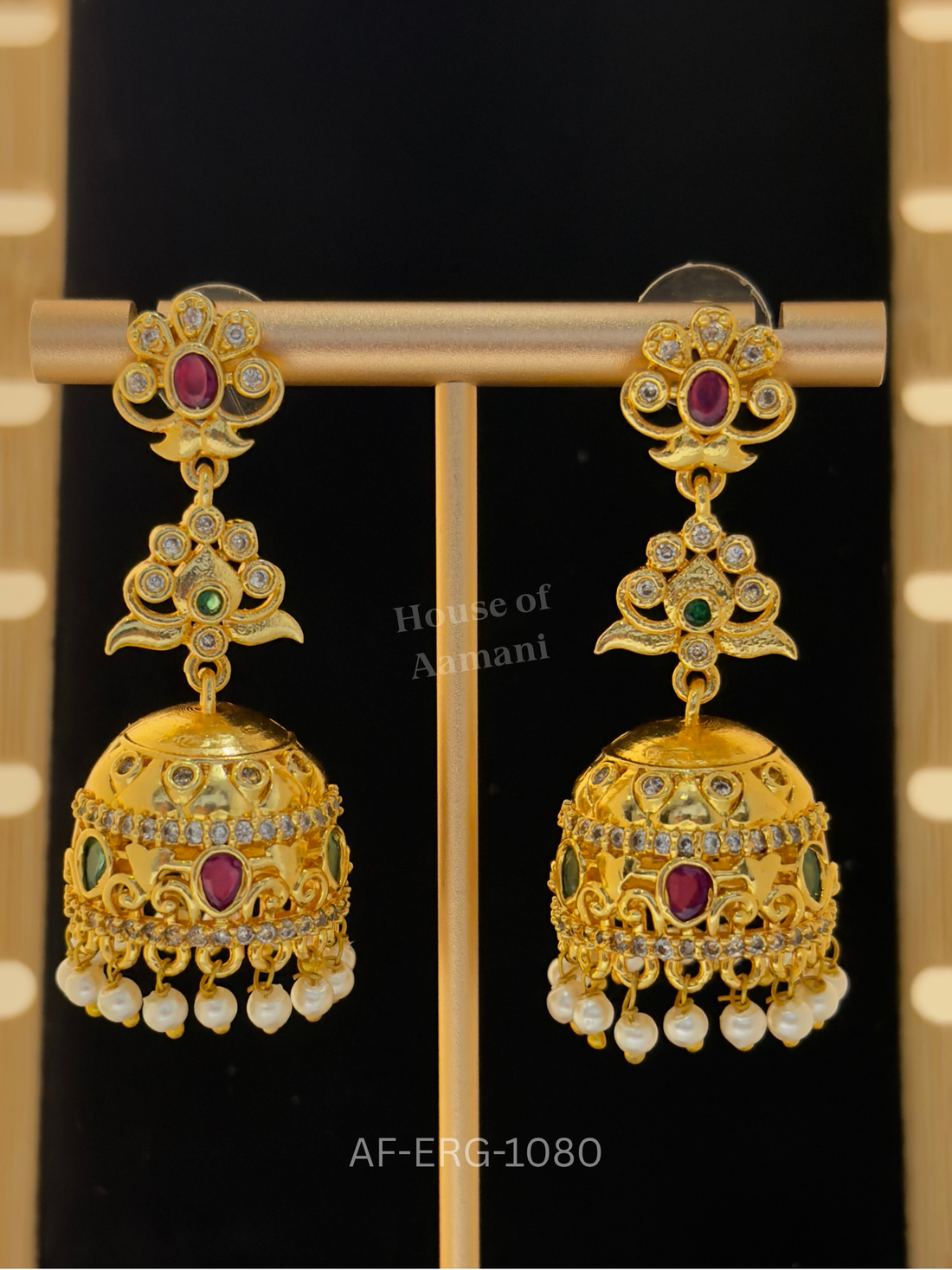 Floral tiered tops lead to a smooth gold dome with crystal bands and a ruby centre, finished with pearl drops.