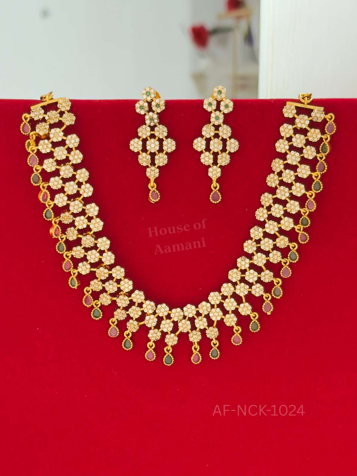A wide choker of sparkling white crystal blossoms fringed with tiny ruby and emerald teardrops, paired with matching earrings.