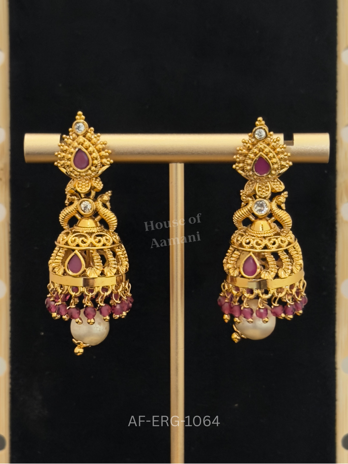 Intricately textured gold jhumkas with a ruby teardrop top, filigree dome, ruby bead fringe, and a large pearl drop.