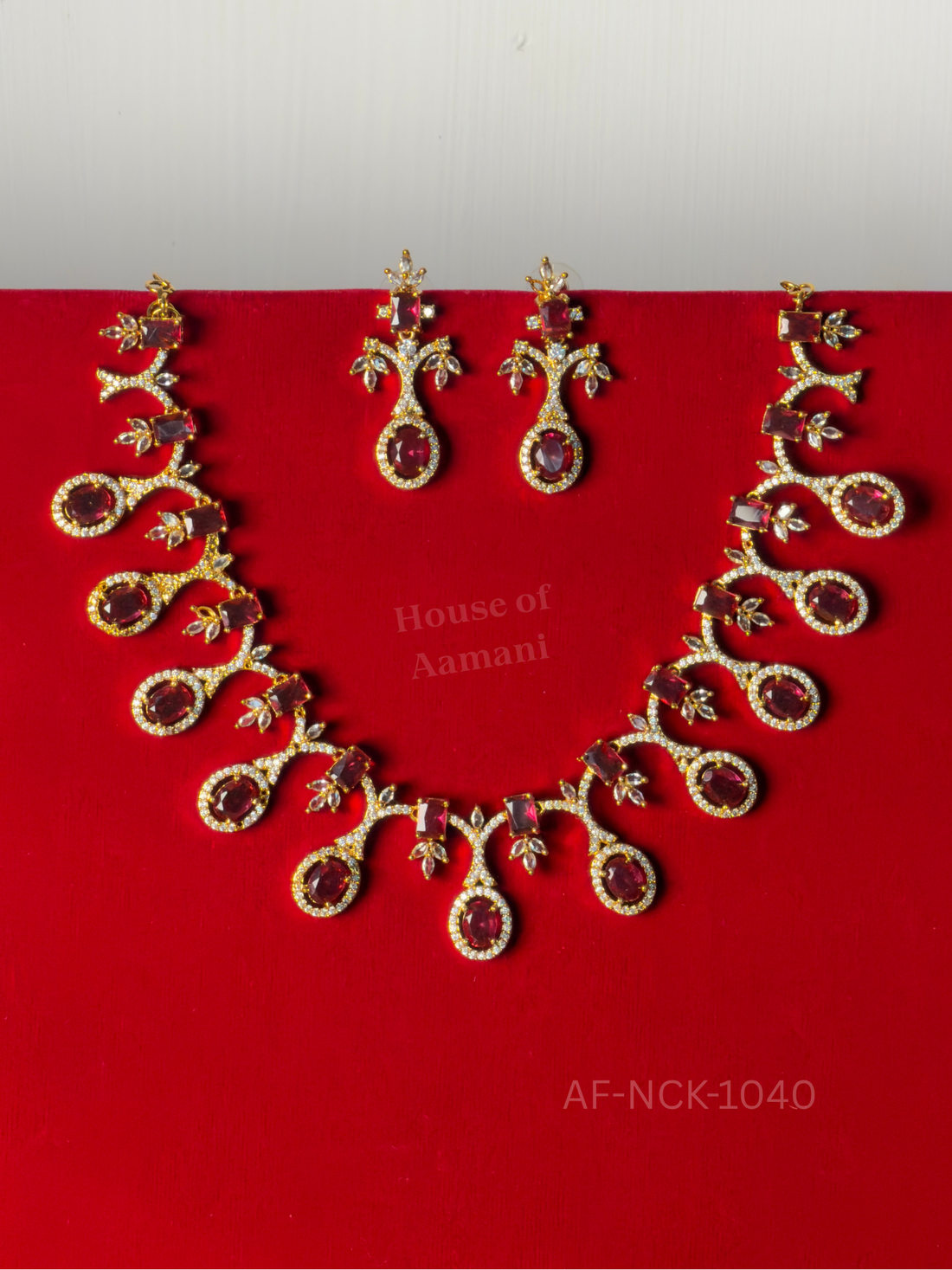 Deep-red oval stones haloed in crystals hang from curling vines with crystal leaf accents, with matching earrings.