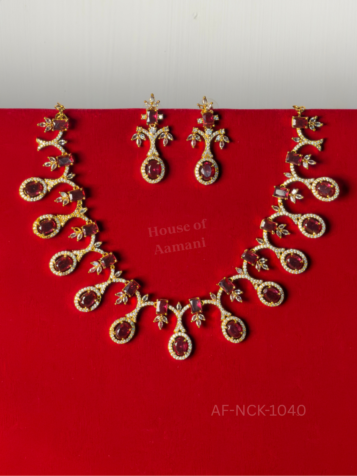 Deep-red oval stones haloed in crystals hang from curling vines with crystal leaf accents, with matching earrings.